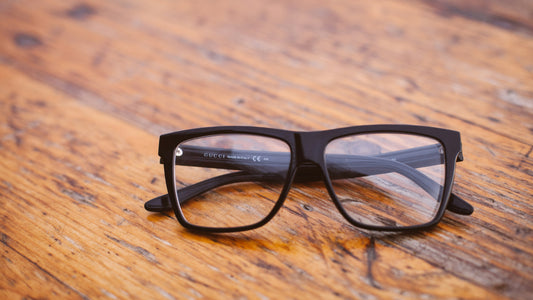 Black framed eyeglasses resting on a rustic wooden table
