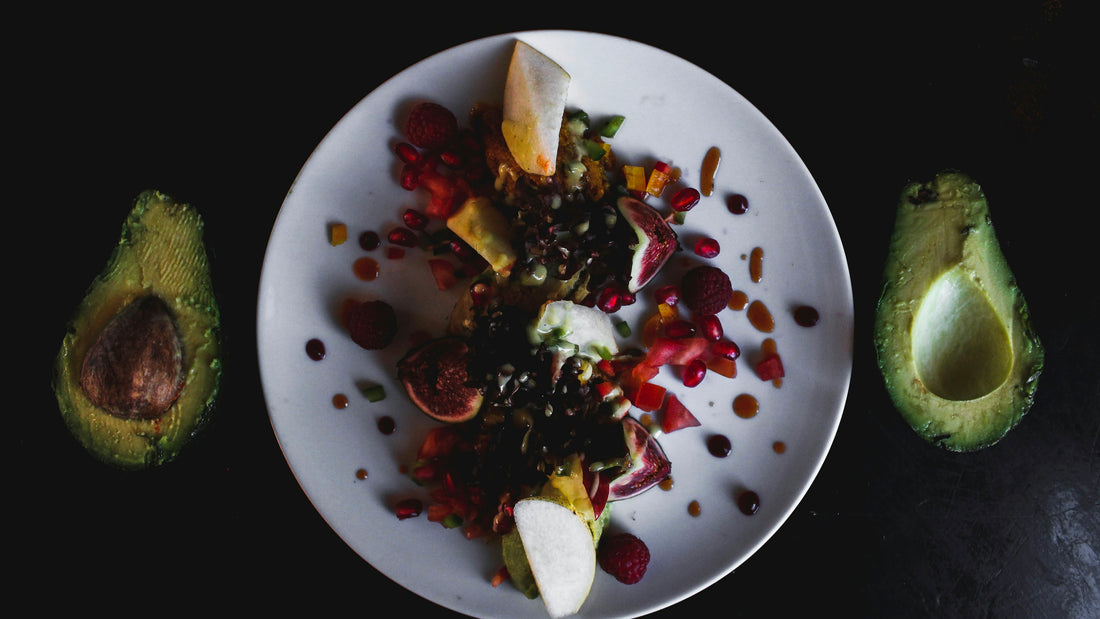 Plate of egg, beetroot and greens salad between avocado halves on black