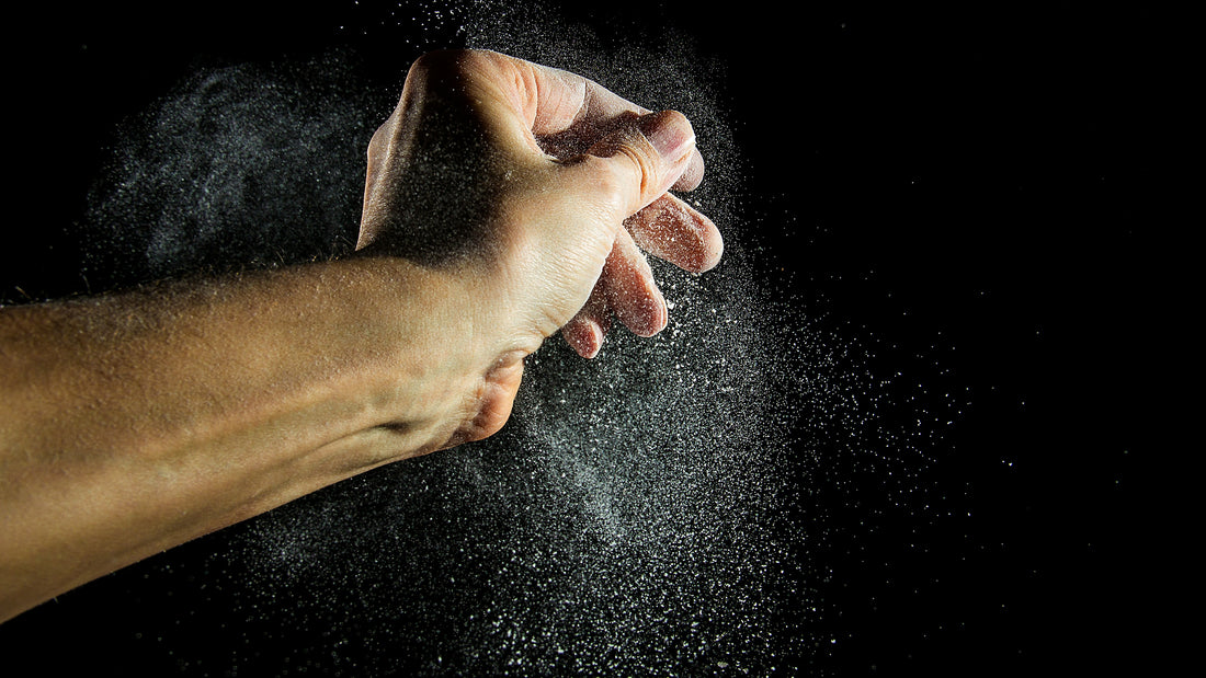 Hand clapping chalk powder into the air against a black background