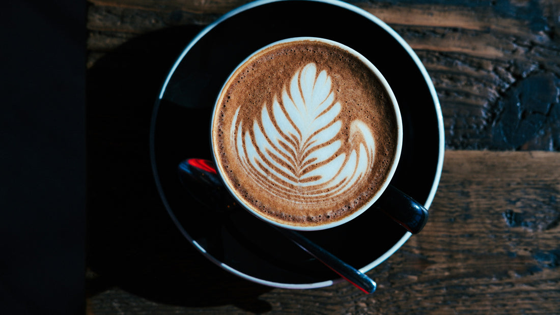 Latte in a black cup on a dark wooden table
