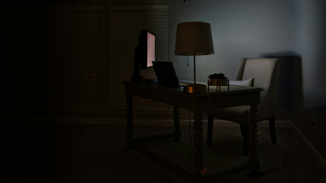 Empty desk and chair in a dark room under a single lamp