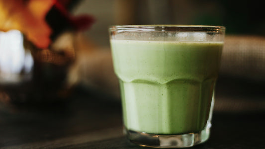 Glass of green smoothie on a dark table in moody light