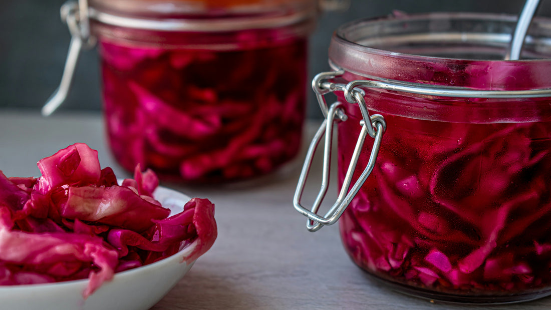 Glass jars of pickled red cabbage with a bowl in front