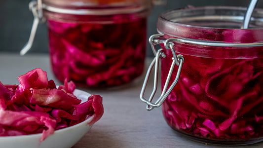 Glass jars of pickled red cabbage with a bowl in front