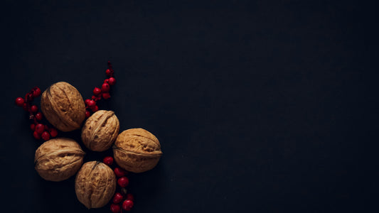 Whole walnuts and red berries on a dark black surface