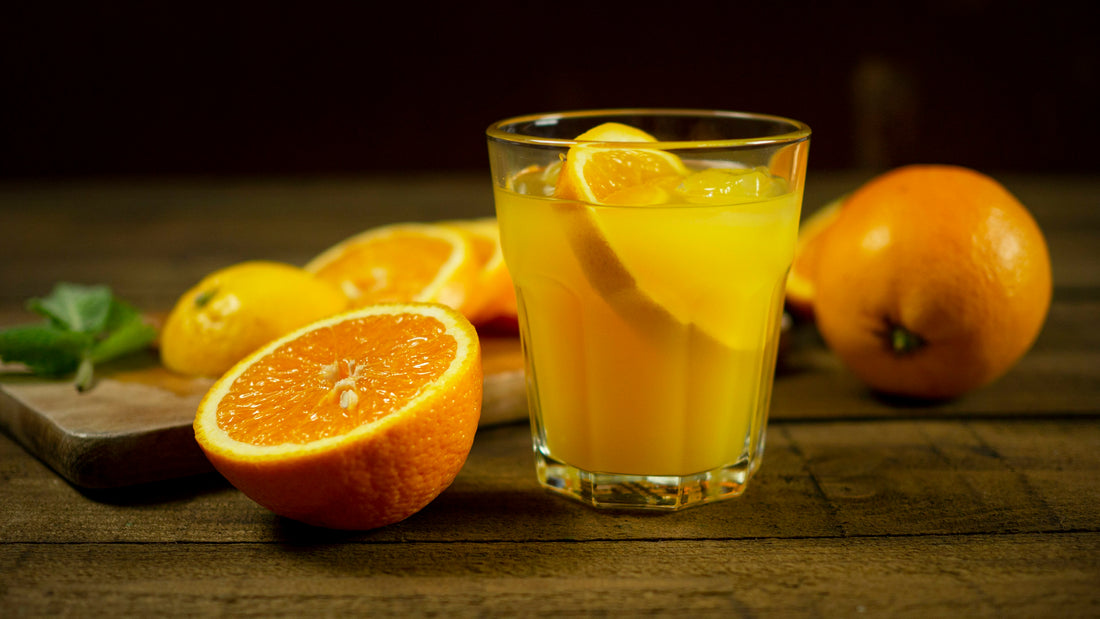 Glass of orange juice with sliced oranges on a dark wooden table