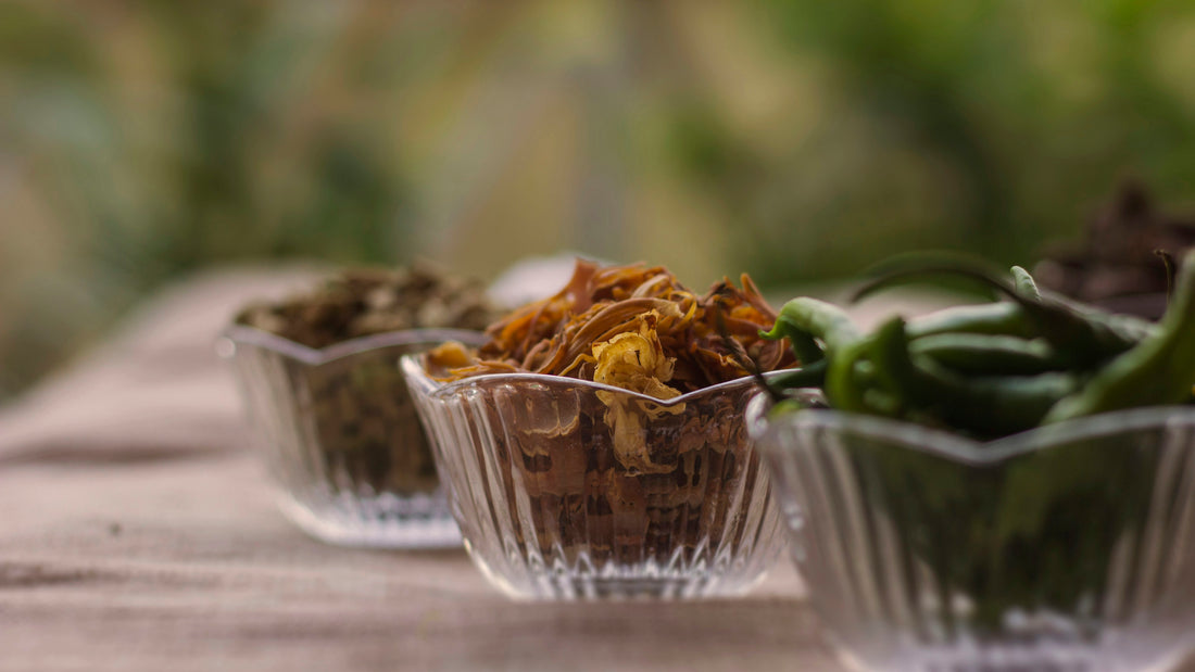 Dried herbs and spices in small glass bowls on a wooden table