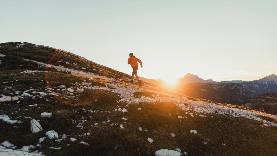 Lone figure moving along a rocky mountain ridge at golden sunset