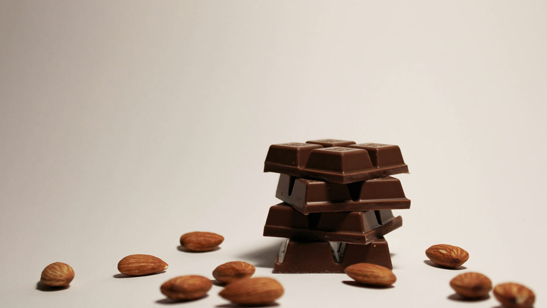 Stacked dark chocolate squares surrounded by whole almonds