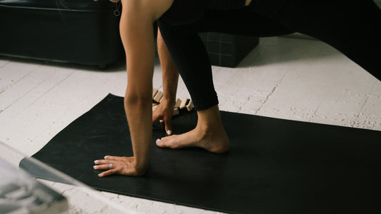 Hands and bare feet on a black yoga mat during a stretch